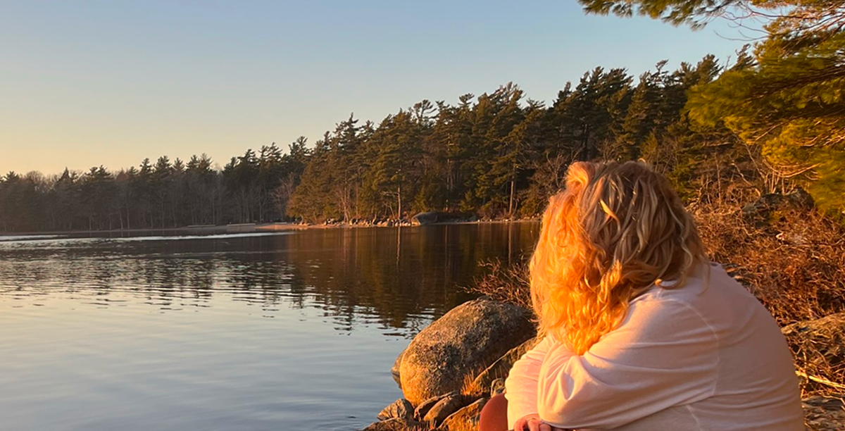 Lan sitting by the lakeshore, sunset.